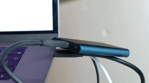 Footage of Guy connecting black usb-c cable t5 ssd to macbook pro with Video stock 105325546