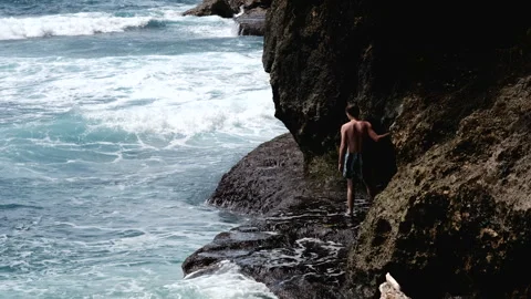 Footage of a guy walking on on surf-filled rocks. Pandan beach, Nusa Penida. Stock Footage 285995942