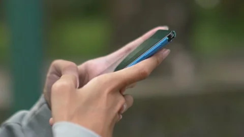 Footage of a hand operating a smartphone in an open green space Stock Footage 232493796