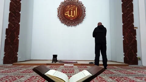 Footage of a man praying in a mosque in front of the mihrab and the name Allah Stock Footage 141358685