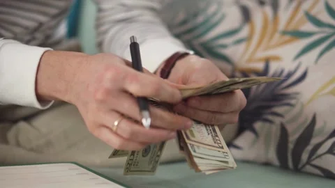 Footage of man sits while counts dollar money at table. Male hands holding .. Stock Footage 266469624