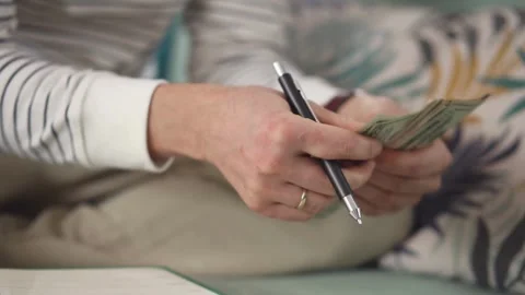 Footage of man sits while counts dollar money at table. Male hands holding .. Stock Footage 266469628
