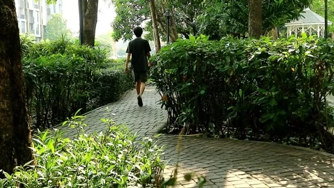 Footage of a man walking for cool down on a garden paving path 스톡 동영상 250403735