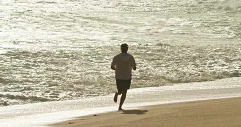Footage of a man while running along the ocean coast Stockbeeldmateriaal 148466509
