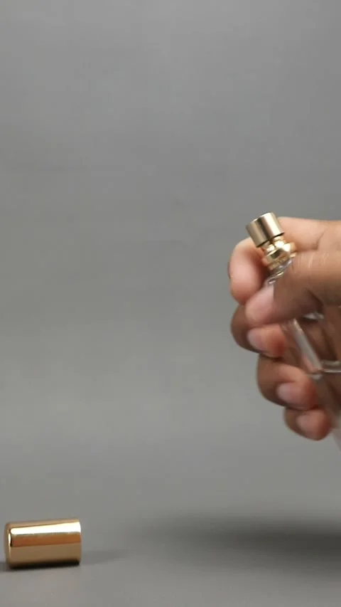 Footage of a man's hand opening the cap of a perfume bottle with a gold col.. Vidéo 331904599