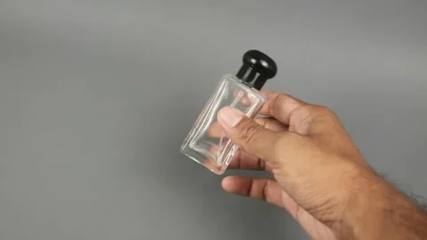 Footage of a man's hand picking up a clear perfume bottle with a black cap .. Vidéo 331904583