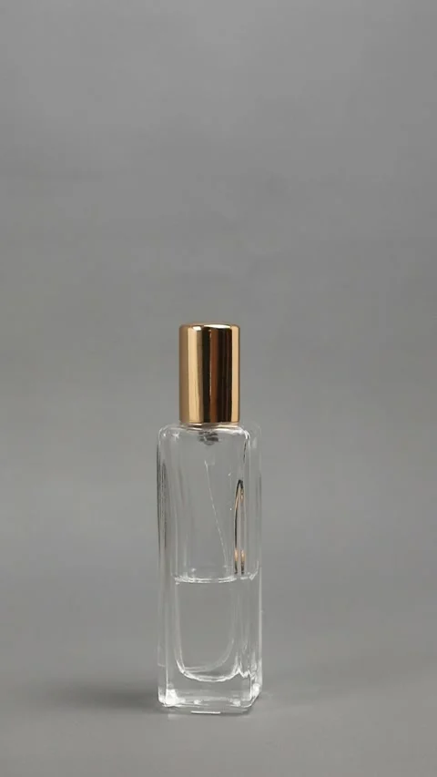 Footage of a man's hand placing a perfume bottle with a gold colored cap on.. Vidéo 331904585