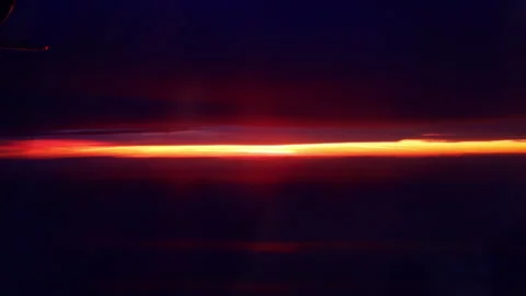Footage of a orange sunset from a plane window. The aircraft is over the clouds 스톡 동영상 347974145