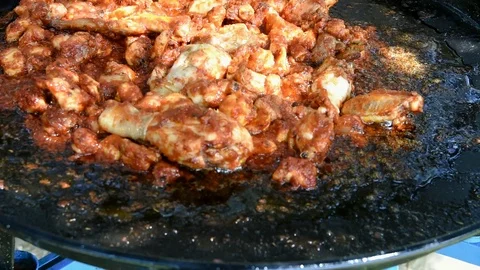 Footage process cooking chicken rabbit meat in paella frying pan skillet on fire Stock Footage 107100645