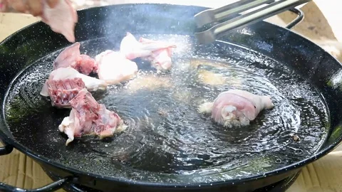Footage of process of making cooking Spanish paella frying rabbit meat in pan Stock Footage 107100729