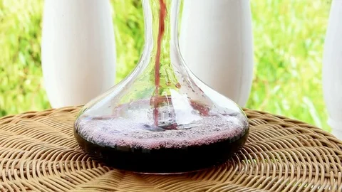 Footage Process of Pouring Red Wine into Glass Decanter on Wicker Table Stock Footage 93287437