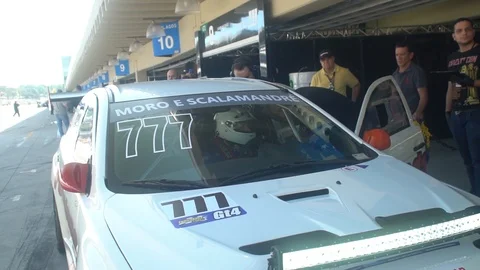 Footage of a racing driver, getting a pep talk from his team, at the Stock Footage 98357390