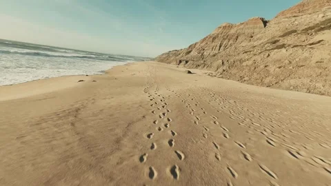 Footage shows footprints trailing along a wide, sandy beach Stock Footage 341827029
