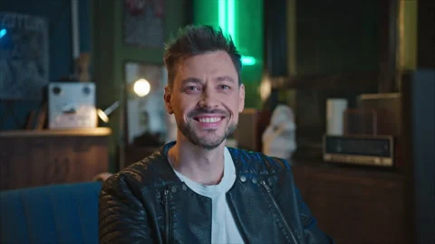 Footage of smiling handsome guy looking at camera while sitting at computer in Stock Footage 238740471