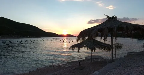 Footage of a sunset at a beach showing two parasols made of palm leaves Stock Footage 67550745