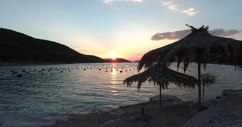 Footage of a sunset at a beach showing two parasols made of palm leaves Stock Footage 67550769