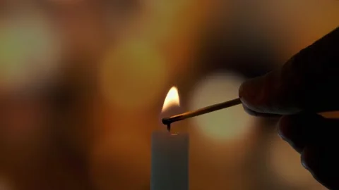 Footage of Using a match, light a candle on on a of colored blurred bokeh Stock Footage 151909139