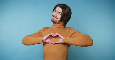 Footage of young joyful man forms a heart shape with his hands, conveying l.. Stock Footage 316922003