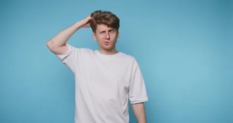 Footage of young man appears puzzled while scratching his head, reflecting .. Stock Footage 314773496