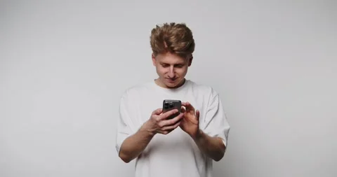 Footage of young man interacts joyfully with his phone, smiling as he engag.. Stock Footage 314522528