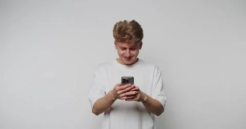 Footage of young man smiles while looking at his smartphone, conveying joy .. Stock Footage 317631703
