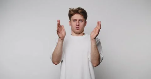 Footage of young man with surprised expression raises hands in dismay, refl.. Stock Footage 314522490