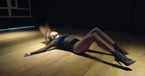 Footage of a young pretty dancer dancing on the floor under the light, 4k Stock Footage 135647203
