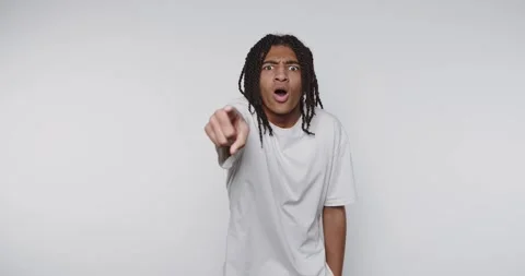 Footage of young surprised man dramatically points at camera on light backg.. Stock Footage 314773573