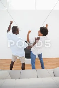 Football fans standing and cheering in front of tv Stock Photos
