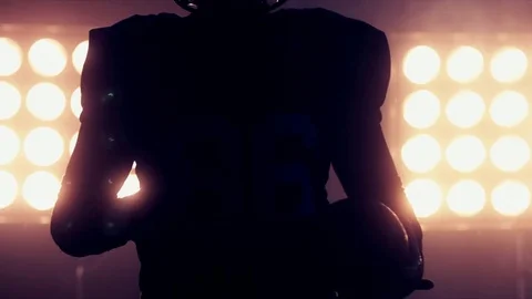 Football player holding a ball in his hands against stadium illumination lights Stock Footage 73103852