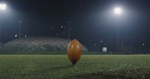 Football player practicing kicking off at night Stock Footage