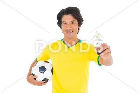 Football player in yellow holding winners trophy Stock Photos