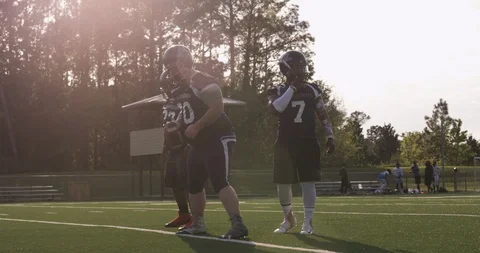 Football players playing football in full uniform, with lens flare Stock Footage
