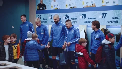 Football players shake hands with children in the locker room Stock Footage