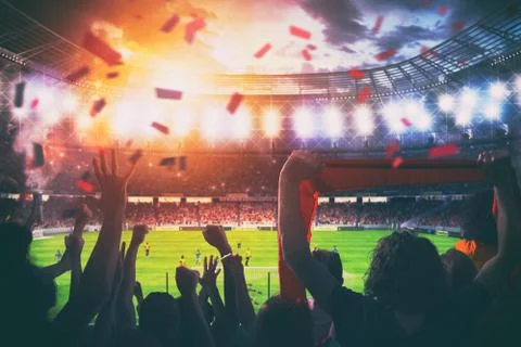 Football scene at night match with cheering fans at the stadium Stock Photos