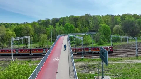 Footbridge with cycle path, bikers, train and old man Stock Footage 242270265