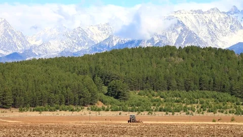 Foothill valley in spring. Tractor harrow ground before sowing cereals Stock Footage 87640592