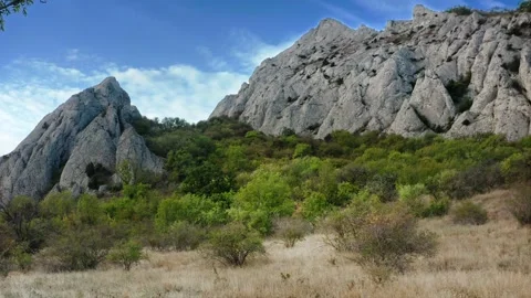 Foothills with dried grass against a mountain range sheltered from the sun and Stock Footage 223048150