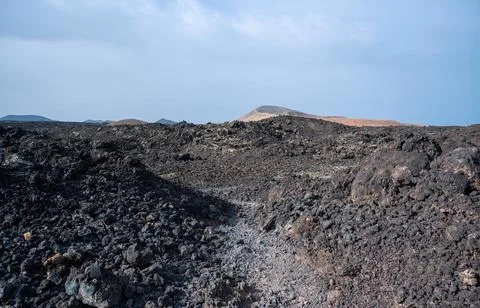 Footpath between lava with views of the Caldera Blanca volcano, Timanfaya, Ca Stock Photos