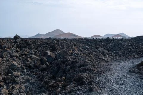 Footpath between lava with views of the Caldera Blanca volcano, Timanfaya, Ca Stock Photos