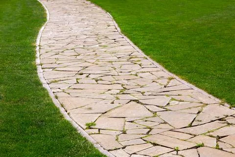 Footpath from different pieces of stone paved with a pattern in a park. Stock Photos
