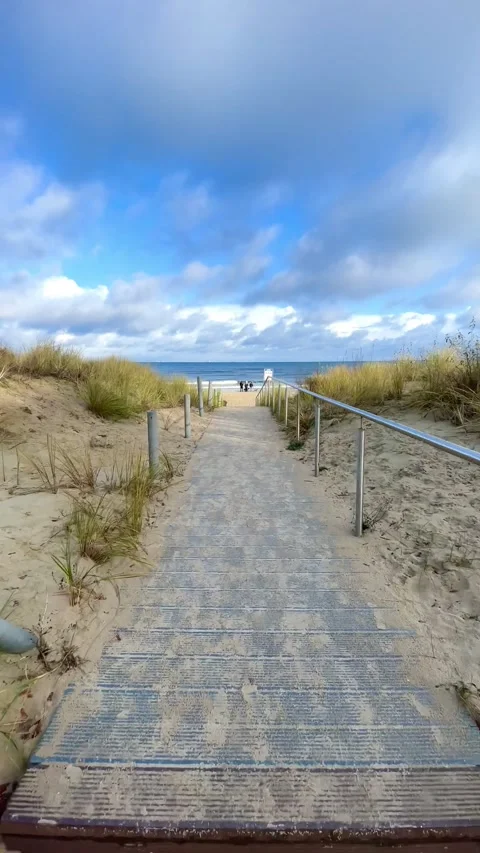 Footpath over sand dunes and beach grass to the blue sea Stock Footage 297612996