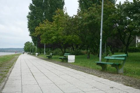 Footpath reached in the trees along the river with benches Stock Photos