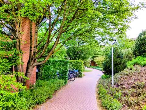 Footpath winds through trees, nature, and a building with Bicycles parked Stock Photos