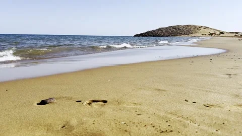A footprint in the sand is waiting to be washed away by the sea wave. 스톡 동영상 343532185