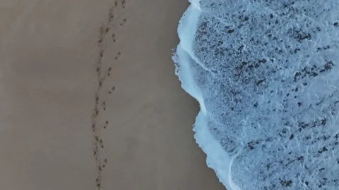 Footprints and a wave on the beach. Stock Footage 230121659