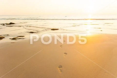Footprints and wave at sunset time. Stock Photos