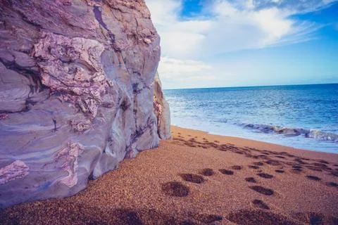 Footprints on the beach by a cliffside Foto stock