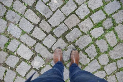 Footprints on a charming cobblestone path with vibrant greenery, inviting 스톡 사진