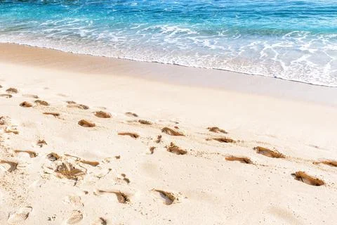 Footprints left behind on a sandy beach by the lapping waves of the ocean Stock Photos
